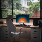 a desk with a computer on it in front of a window