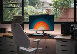a desk with a computer on it in front of a window