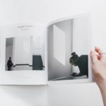 person reading book on white surface