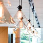 Warm-toned Edison bulb pendant lighting hanging overhead a workstation in an office setting.