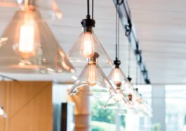 Warm-toned Edison bulb pendant lighting hanging overhead a workstation in an office setting.