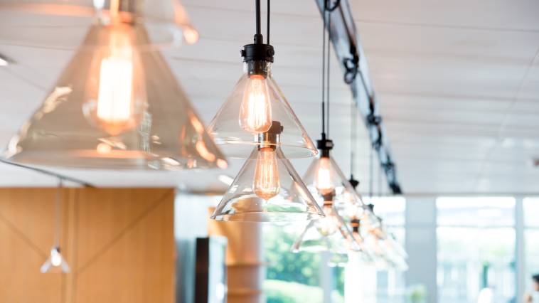 Warm-toned Edison bulb pendant lighting hanging overhead a workstation in an office setting.