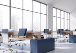 A panoramic view shows an empty commercial office space filled with desks, empty chairs, and computers.