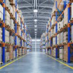 An organized warehouse building entire of boxes and materials stacked up towards the ceiling, with an industrial background.